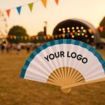 Custom handheld fans with festival branding displayed outdoors in a lively summer festival setting